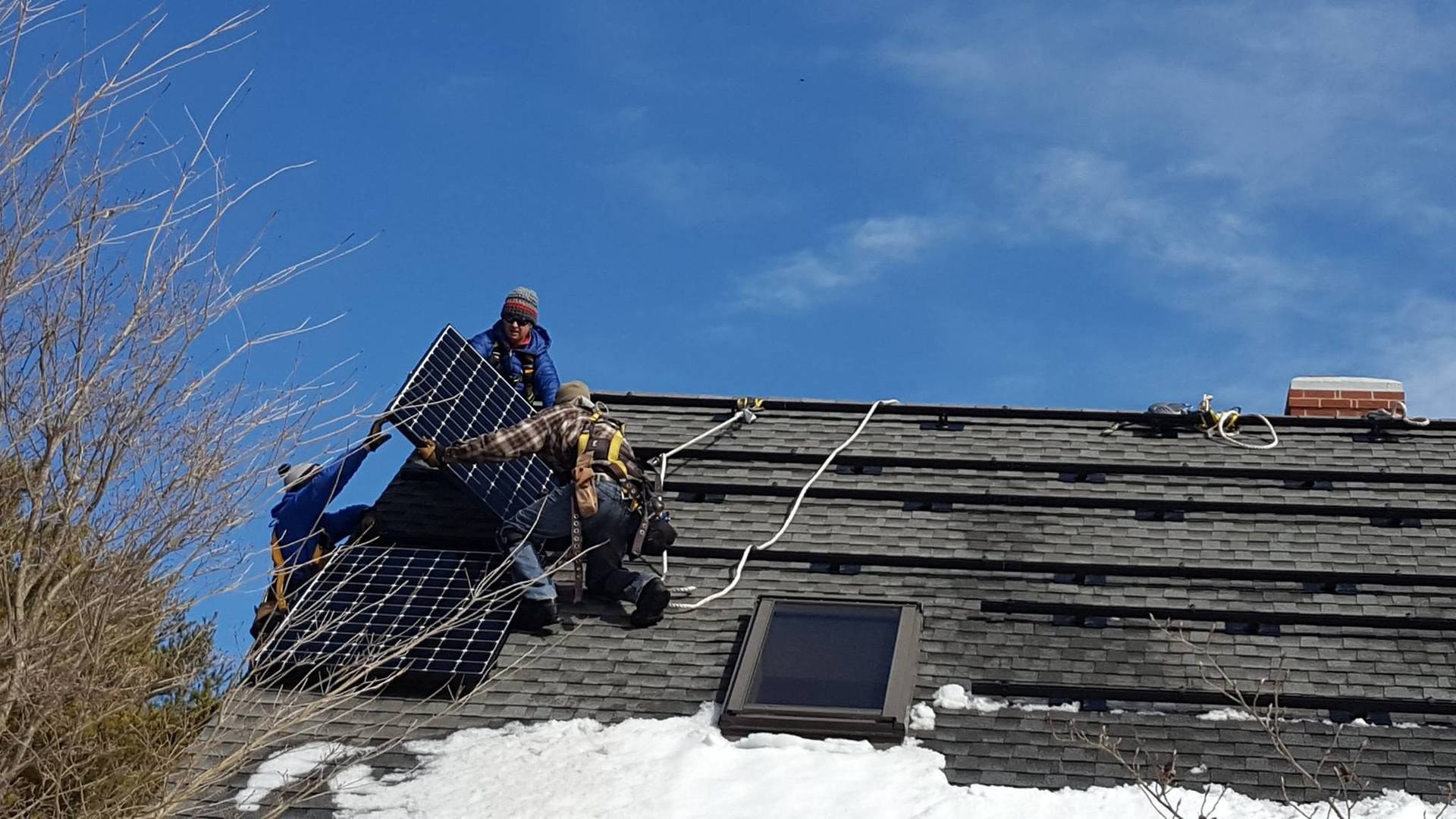 Installer lifting a solar panel onto a roof
