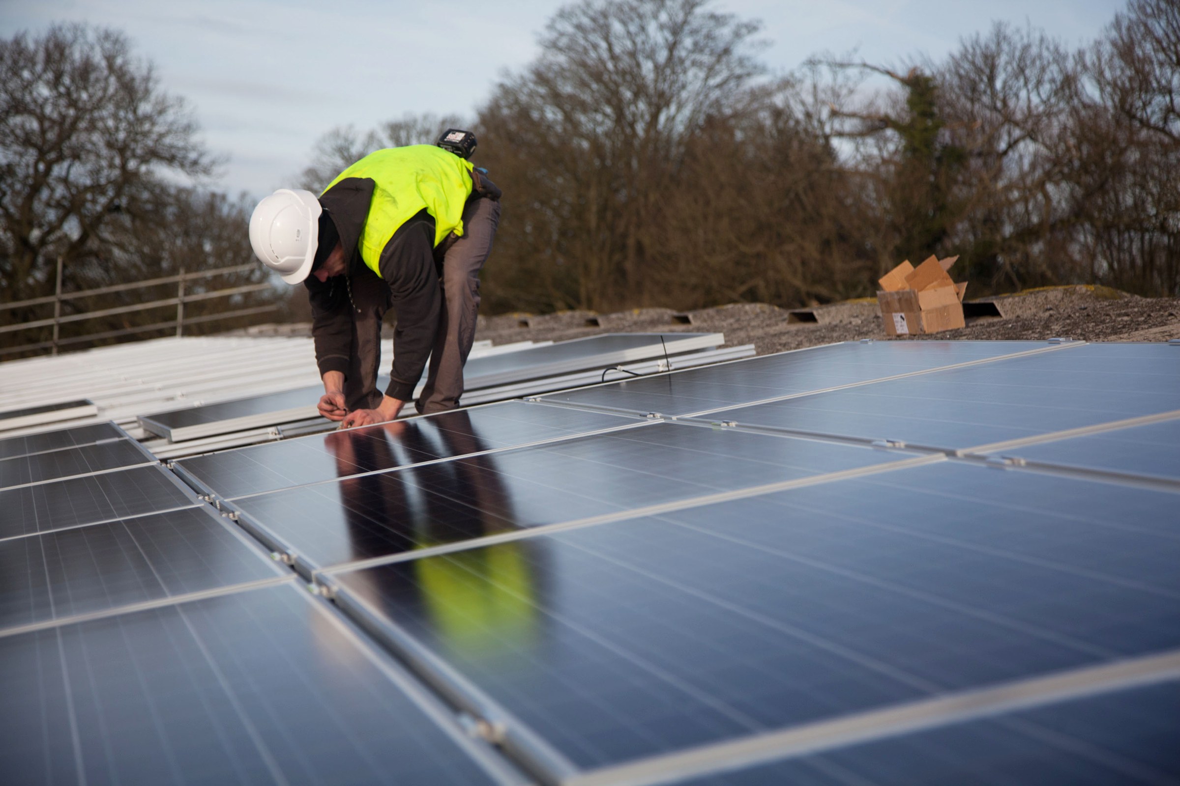Installer in a hi-vis vest fixing solar panels on a roof